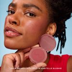 A person holds Tower 28 Beauty’s GetSet Powder Blush in the shade Sawtelle Slushie with a swatch of rose pigment on their cheek. [Sawtelle Slushie]