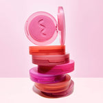 A stack of Tower 28 Beauty GetSet Powder Blush compacts are shown, with the top compact open to reveal the vibrant pink shade Malibu Cooler. [Malibu Cooler, Feliz Fresca, Culver Crush, Long Beach Iced Tea, Samo Spritzer, Sawtelle Slushie, Pali Punch]