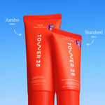 Two red tubes of Tower 28 cream labeled 'Jumbo' and 'Standard' on a blue background. [Shared]