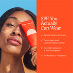 A person holds up a bottle of Tower 28 Beauty 's SOS FaceGuard SPF 30 while wearing swatches of the product on their cheek. Text highlights features including a gentle mineral formula, no alcohol or fragrance, and dermatologist approval.  [Shared: SOS FaceGuard SPF 30]