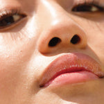 A model wearing the Tower 28 Beauty ShineOn Lip Jelly in the shade Oat on her lips. [Oat]